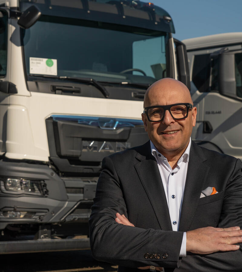 Fotografie eines Geschäftsmannes, der vor einem LKW steht.